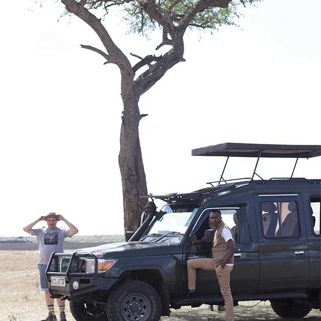 Two men standing under Maasai Mara Icon Tree